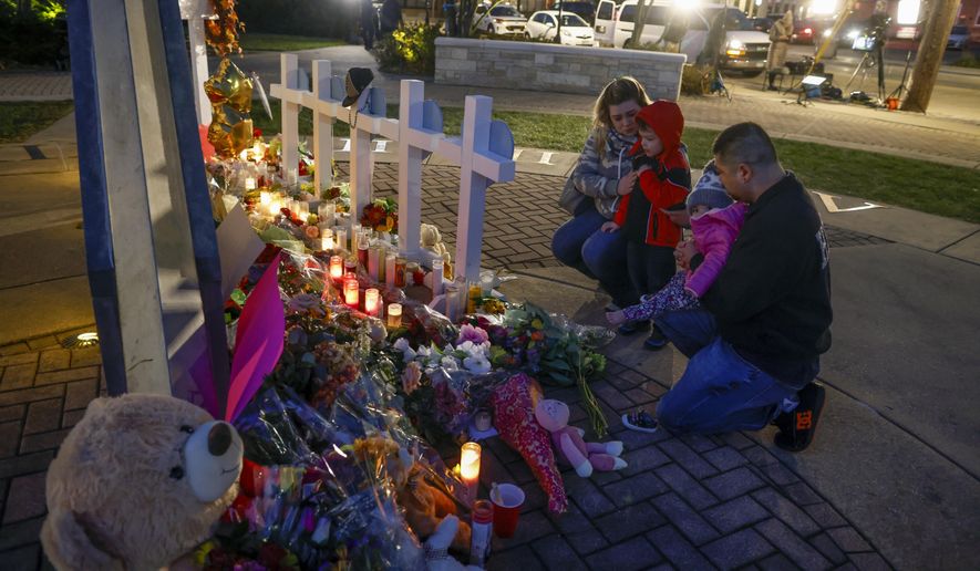 A family visits a memorial at Veteran&#39;s Park for the victims of Sunday, Nov. 21, 2021&#39;s deadly Christmas parade crash in Waukesha, Wis., Tuesday, Nov. 23, 2021. (AP Photo/Jeffrey Phelps File)
