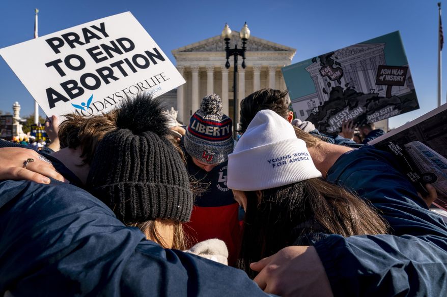 A group of anti-abortion protesters pray together in front of the U.S. Supreme Court, Wednesday, Dec. 1, 2021, in Washington, as the court hears arguments in a case from Mississippi, where a 2018 law would ban abortions after 15 weeks of pregnancy, well before viability. (AP Photo/Andrew Harnik)