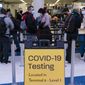 FILE - Travelers wait in line for screening near a sign for a COVID-19 testing site at the Los Angeles International Airport in Los Angeles on Nov. 24, 2021. Beginning next week, travelers heading to the U.S. will be required to show evidence of a negative test for the virus within one day of boarding their flight. The previous period was three days. (AP Photo/Jae C. Hong, File)