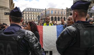 An anti heath pass demonstrator holds a French flag as he faces police officers outside the Constitutional Council in Paris, Thursday, Aug. 5, 2021. The coronavirus&#39;s omicron variant kept a jittery world off-kilter Wednesday Dec. 1, 2021, as reports of infections linked to the mutant strain cropped up in more parts of the globe, and one official said that the wait for more information on its dangers felt like “an eternity.” (AP Photo/Michel Euler, File)