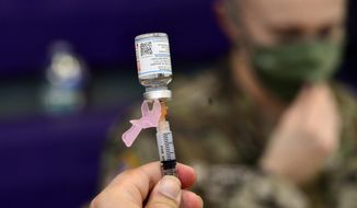 Spc. Brady McNeil, a radiologist with the Vermont Army National Guard, draws up a dose of the Moderna COVID-19 during a vaccination clinic at the Brattleboro Area Middle School, April 14, 2021, in Brattleboro, Vt. The Army says it will start booting out soldiers who refuse to take the COVID-19 shot only days after yet another fully-vaccinated and boosted senior Pentagon official tested positive for the coronavirus. (Kristopher Radder/The Brattleboro Reformer via AP, File)