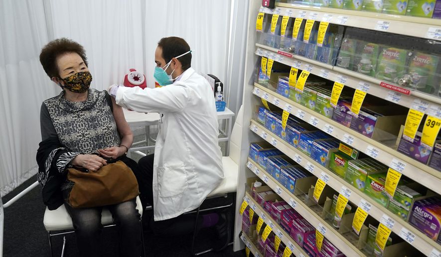 Pharmacist Todd Gharibian, right, administers a dose of the Moderna COVID-19 vaccine to Toshiko Sugiyama, left, at a CVS Pharmacy branch on March 1, 2021, in Los Angeles. A rush of vaccine-seeking customers and staff shortages are squeezing drugstores around the country. That has led to frazzled workers and even temporary pharmacy closures.   (AP Photo/Marcio Jose Sanchez, File)