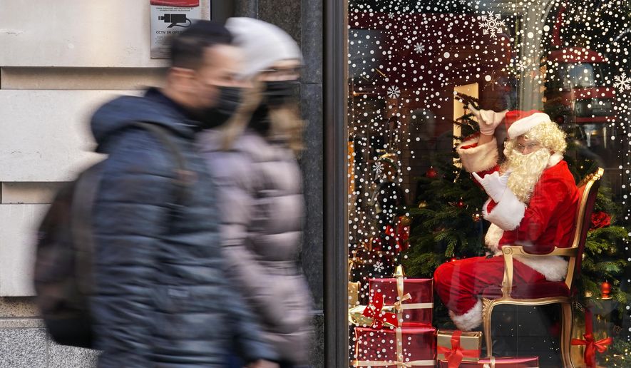 A man dressed as Santa Claus gestures as people walk past, in London, Saturday, Dec. 4, 2021. Britain says it will offer all adults a booster dose of vaccine within two months to bolster the nation&#x27;s immunity as the new omicron variant of the coronavirus spreads. New measures to combat variant came into force in England on Tuesday, with face coverings again compulsory in shops and on public transport. (AP Photo/Alberto Pezzali)