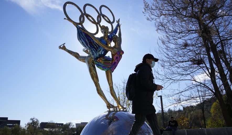 A visitor to the Shougang Park walks past the a sculpture for the Beijing Winter Olympics in Beijing, China, Tuesday, Nov. 9, 2021. China on Monday, Dec. 6, 2021, threatened to take &quot;firm countermeasures&quot; if the U.S. proceeds with a diplomatic boycott of February&#39;s Beijing Winter Olympic Games. (AP Photo/Ng Han Guan)