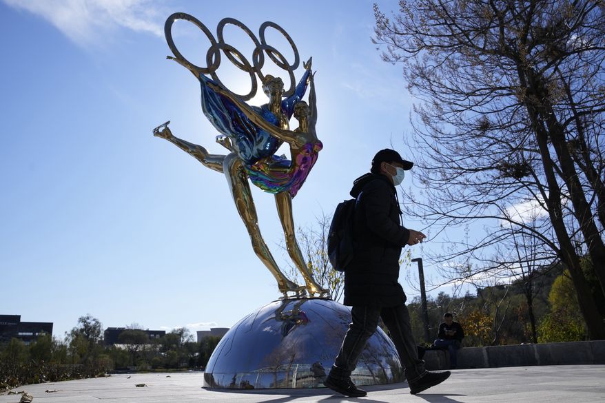 A visitor to the Shougang Park walks past the a sculpture for the Beijing Winter Olympics in Beijing, China, Tuesday, Nov. 9, 2021. China on Monday, Dec. 6, 2021, threatened to take &quot;firm countermeasures&quot; if the U.S. proceeds with a diplomatic boycott of February&#x27;s Beijing Winter Olympic Games. (AP Photo/Ng Han Guan)