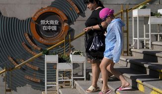 A woman and a child walk by a map showing Evergrande development projects in China at an Evergrande city plaza in Beijing on Sept. 21, 2021. Shares were mostly lower in Asia on Monday after troubled Chinese property developer Evergrande warned late Friday it may run out of money. (AP Photo/Andy Wong)