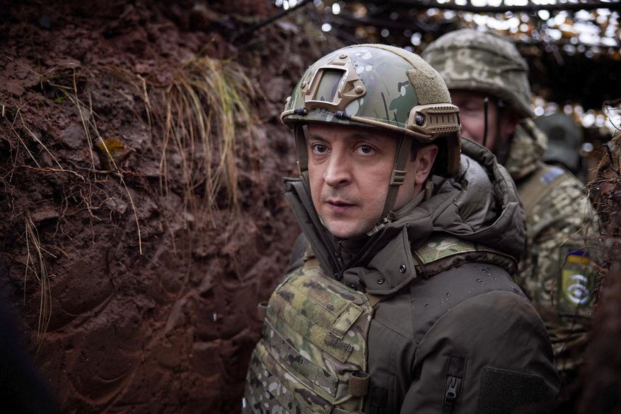 Ukrainian President Volodymyr Zelenskyy, walks under a camouflage net in a trench as he visits the war-hit Donetsk region, eastern Ukraine, Monday, Dec. 6, 2021. (Ukrainian Presidential Press Office via AP)