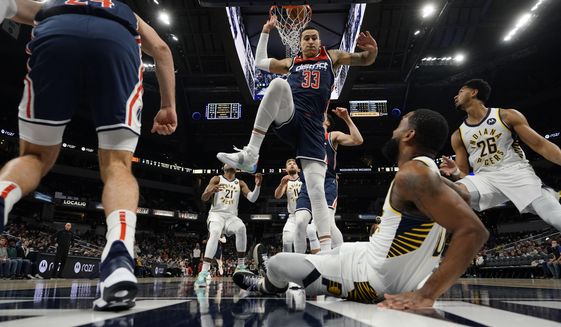 Washington Wizards forward Kyle Kuzma (33) comes down after failing to block a shot by Indiana Pacers guard Brad Wanamaker, bottom right foreground, during the first half of an NBA basketball game in Indianapolis, Monday, Dec. 6, 2021. (AP Photo/AJ Mast)