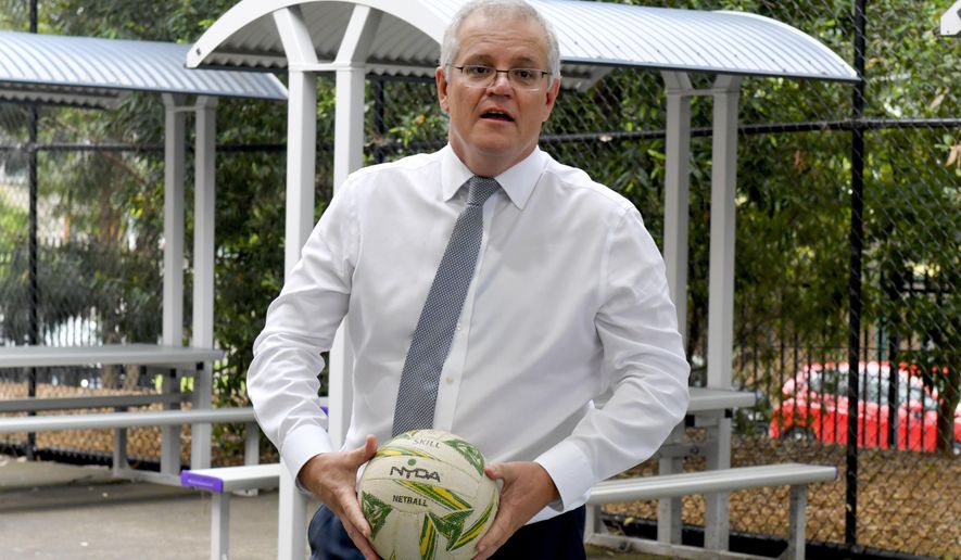 Australian Prime Minister Scott Morrison holds a ball during a visit to a school in Sydney, Wednesday, Dec. 8, 2021. Morrison said Wednesday it will join the U.S. in a diplomatic boycott of the Beijing Winter Games over human rights concerns. (Mick Tsikas/AAP Image via AP)