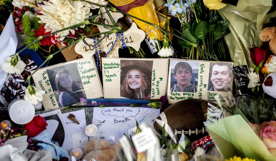 Photographs of four students — Hana St. Juliana, 14, Madisyn Baldwin, 17, Tate Myre, 16, and Justin Shilling, 17 — sit among bouquets of flowers, teddy bears and other personal items left at the memorial site on Tuesday, Dec. 7, 2021, outside Oxford High School in Oxford, Mich., after a 15-year-old allegedly killed these four classmates, and injured seven others in a shooting inside the northern Oakland County school one week earlier. (Jake May/The Flint Journal via AP)