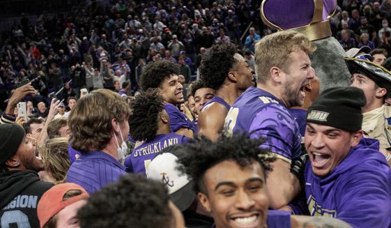 Fans and players celebrate on the court after James Madison defeated Virginia 52-49 in an NCAA college basketball game, Tuesday, Dec. 7, 2021, in Harrisonburg, Va. (Daniel Lin/Daily News-Record via AP)