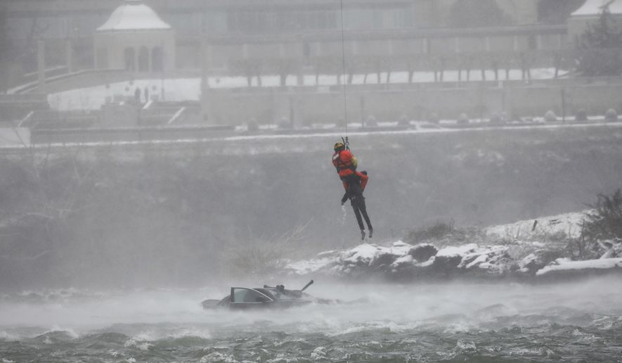A U.S. Coast Guard rescue diver removes a passenger from a vehicle in the water at the brink of Niagara Falls, N.Y. on Wednesday, Dec. 8, 2021. (Derek Gee/Buffalo News via AP)