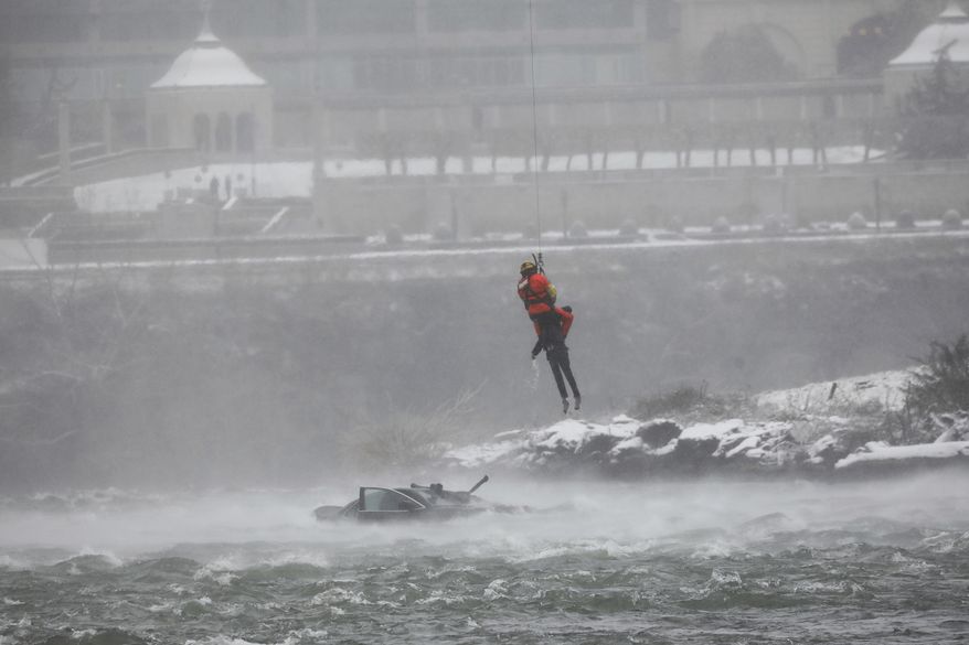 A U.S. Coast Guard rescue diver removes a passenger from a vehicle in the water at the brink of Niagara Falls, N.Y. on Wednesday, Dec. 8, 2021. (Derek Gee/Buffalo News via AP)