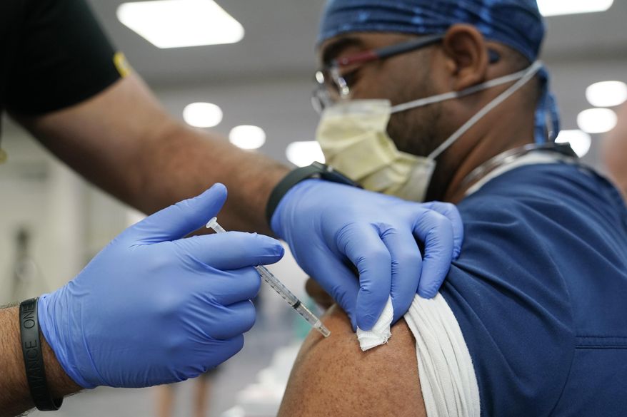A healthcare worker receives a Pfizer COVID-19 booster shot at Jackson Memorial Hospital in Miami on Oct. 5, 2021, in Miami. Pfizer said Wednesday, Dec. 8, 2021, that a booster dose of its COVID-19 vaccine may protect against the new omicron variant even though the initial two doses appear significantly less effective. (AP Photo/Lynne Sladky) **FILE**