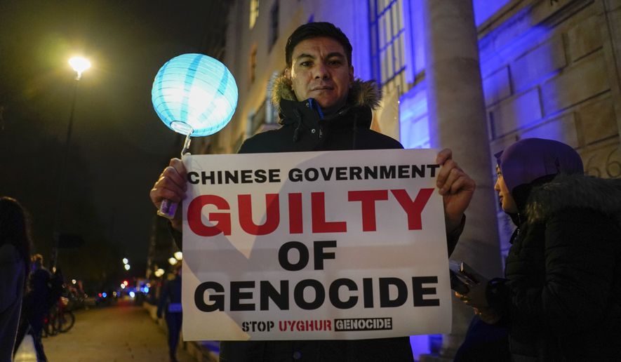 A demonstrator holds a placard and a lantern during a demonstration outside the Chinese Embassy in London, Thursday, Dec. 9, 2021. An independent, unofficial body set up by a prominent British barrister to assess evidence on China’s alleged rights abuses against the Uyghur people concluded Thursday that the Chinese government committed genocide and crimes against humanity. (AP Photo/Alberto Pezzali)