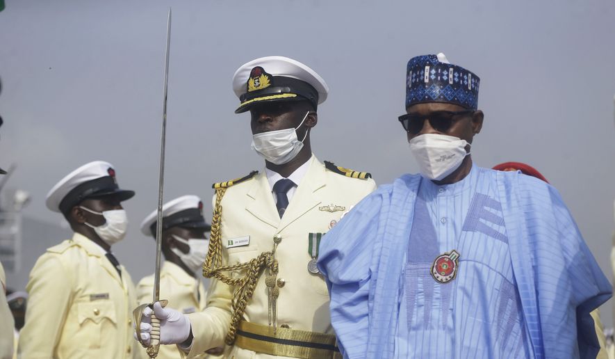 Nigerian President Muhammadu Buhari, right, inspects the honor guard, during a Naval ceremony in Lagos, Nigeria, Thursday, Dec. 9, 2021. The Nigerian navy on Thursday inducted new boats, ships and helicopter to help secure its waters and fight piracy in the highly perilous sea in the Gulf of Guinea. Nigerian President Muhammadu Buhari said the new platforms will “greatly bolster the efforts of the service in securing Nigerian maritime environment.” (AP Photo/Sunday Alamba) ** FILE **