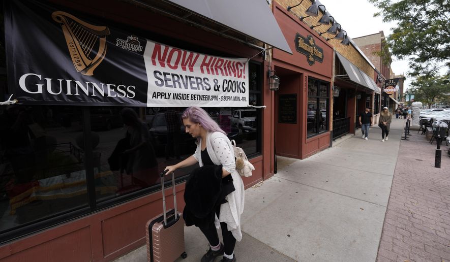 A traveler wheels her baggage past a now hiring sign outside a bar and restaurant Saturday, Oct. 9, 2021, in Sioux Falls, S.D. (AP Photo/David Zalubowski) ** FILE **