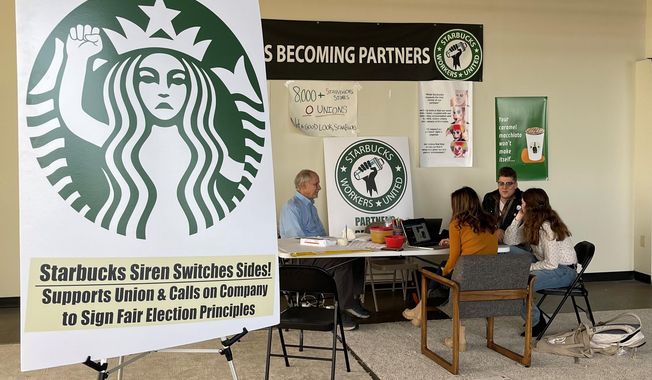 FILE- Richard Bensinger, left, who is advising unionization efforts, along with baristas Casey Moore, right, Brian Murray, second from left, and Jaz Brisack, second from right, discuss their efforts to unionize three Buffalo-area stores, inside the movements headquarters on Oct. 28, 2021 in Buffalo, N.Y. The National Labor Relations Board is scheduled to count ballots Thursday, Dec. 9, 2021, from union elections held at three separate Starbucks stores in the Buffalo area. Around 111 Starbucks workers from the three stores were eligible to vote by mail starting last month.(AP Photo/Carolyn Thompson, File)