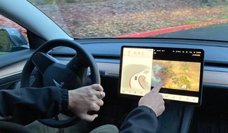 Vince Patton, a new Tesla owner, demonstrates on Wednesday, Dec. 8, 2021, on a closed course in Portland, Ore., how he can play video games on the vehicle&#39;s console while driving. Patton, of Portland, Ore., filed a complaint with federal regulators after discovering the feature in his new car. (AP Photo/Gillian Flaccus)