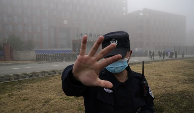 A security person moves journalists away from the Wuhan Institute of Virology after a World Health Organization team arrived for a field visit in Wuhan in China&#x27;s Hubei province on Feb. 3, 2021. Nearly two years into the COVID-19 pandemic, the origin of the virus tormenting the world remains shrouded in mystery. (AP Photo/Ng Han Guan, File)