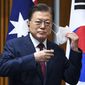 South Korean President Moon Jae-in removes his mask as he witnesses a signing ceremony at Parliament House, in Canberra, Australia, Monday, Dec. 13, 2021. Moon is on a two-day official visit to Australia. (Lukas Coch/Pool Photo via AP)