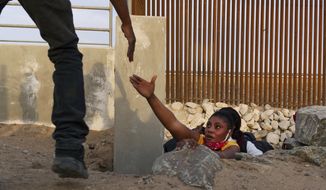 A Haitian migrant family member reaches out for help while emerging from a rocky canal adjacent to a gap in the U.S. border wall in Yuma, Ariz., Wednesday, June 9, 2021. Yuma Mayor Doug Nicholls says an emergency situation in the southwestern Arizona border city has eased with federal officials moving in additional personnel in response to thousands of migrants. (AP Photo/Eugene Garcia) **FILE**