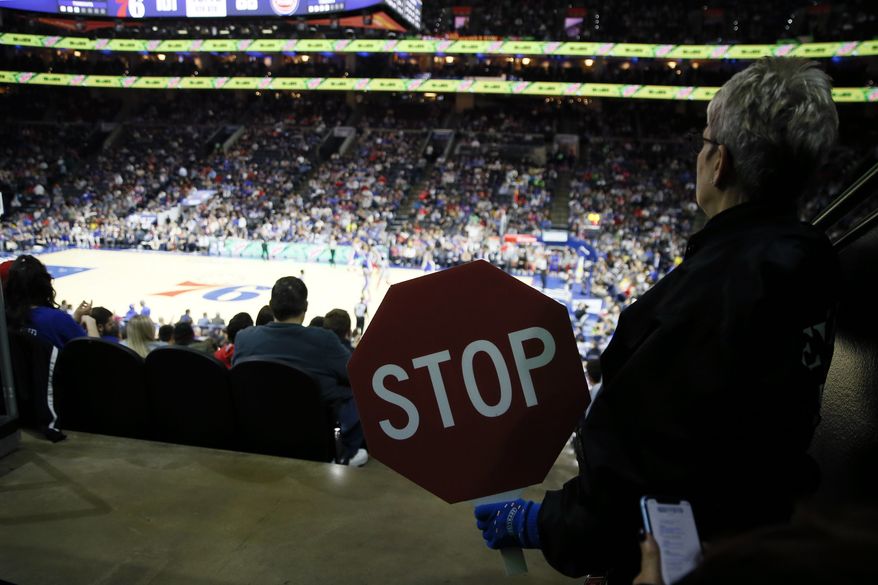 FILE - An usher at the Wells Fargo Center holds a Stop sign during an NBA basketball game between the Philadelphia 76ers and the Detroit Pistons, Wednesday, March 11, 2020, in Philadelphia. Philadelphia officials announced Monday, Dec. 13, 2021 that proof of vaccination will be required starting Jan. 3 for bars, restaurants, indoor sporting events, movie theaters and other places where people eat indoors close to each other. (AP Photo/Matt Slocum, File)