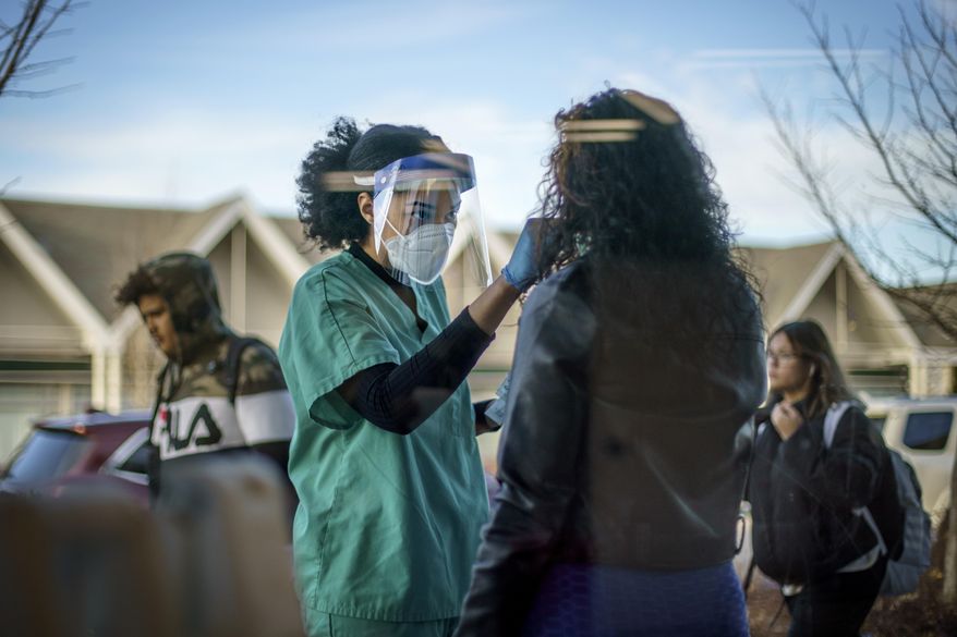 Maya Goode, a COVID-19 technician, performs a test on Jessica Sanchez outside Asthenis Pharmacy in Providence, R.I., Dec. 7, 2021. As the omicron variant sparks worldwide fears of renewed virus outbreaks, Americans’ worries about infection are again on the rise. But fewer say that they are regularly wearing masks or isolating compared with the beginning of the year. (AP Photo/David Goldman, File)
