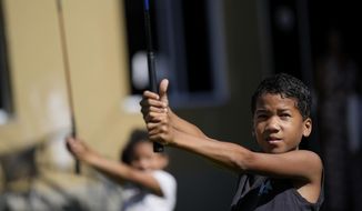 Children learn the basics of golf from caddie Marcelo Modesto on the grounds of the Nusacquilombo cultural center in Cidade de Deus or City of God favela, in Rio de Janeiro, Brazil, Thursday, Dec. 9, 2021. Modesto from one of Rio&#x27;s poorest neighborhoods works at one of the seaside city&#x27;s most exclusive golf courses, earning a comfortable living guiding wealthy patrons around the fairways and greens of the course. Now he is sharing his golf skills with kids from his favela. (AP Photo/Silvia Izquierdo) **FILE**