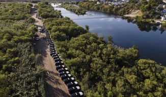 A line of Texas Department of Safety vehicles line up on the Texas side of the Rio Grande with Mexico visible, right, near an encampment of migrants, many from Haiti, Wednesday, Sept. 22, 2021, in Del Rio, Texas. (AP Photo/Julio Cortez, File)