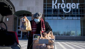 FILE - A shopper loads his car with groceries at the Kroger in Novi, Mich on Jan. 23, 2021.  Kroger says, Tuesday, Dec. 14,  it is modifying some of its COVID-19 policies. Unvaccinated workers will no longer receive certain COVID-19 leave benefits if they get the virus, and some who refuse the shot will also have to pay a monthly health insurance surcharge. (Nic Antaya/Detroit News via AP)