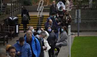 People queue up to go for coronavirus booster jabs at St Thomas&#39; Hospital, in London, Tuesday, Dec. 14, 2021. Long lines have formed for booster shots across England as the U.K. government urged all adults to protect themselves against the omicron variant. (AP Photo/Matt Dunham)