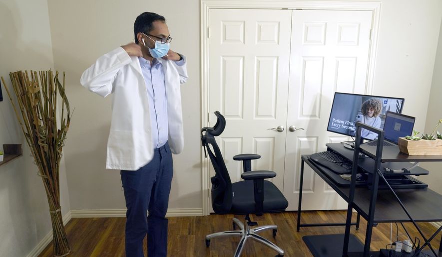 Medical director of Doctor on Demand Dr. Vibin Roy prepares to conduct an online visit with a patient from his work station at home, April 23, 2021, in Keller, Texas.  Comfort levels with remote care can vary depending on factors like age, income level or race, according to the survey from The Associated Press-NORC Center for Public Affairs Research. (AP Photo/LM Otero) **FILE**