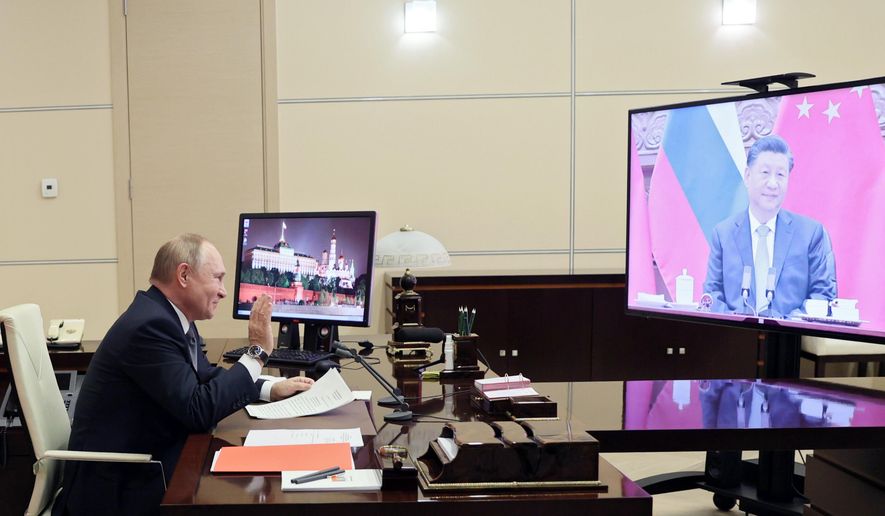 Russian President Vladimir Putin gestures during his videoconference with Chinese President Xi Jinping, right on the screen, in Moscow, Russia, Wednesday, Dec. 15, 2021. Putin and Xi have held a video call to discuss bilateral relations and international affairs. The summit Wednesday comes amid heightened tensions between Moscow and the West over a Russian troop buildup near Ukrainian borders that is stoking fears of a possible invasion. (Mikhail Metzel, Sputnik, Kremlin Pool Photo via AP)