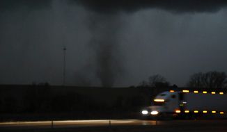A tornado approaches Interstate 80 near Atlantic, Iowa, as a semi truck rolls eastward on Wednesday, Dec. 15, 2021. A band of strong storms swept across much of the plains states on Wednesday, producing powerful wind gusts and tornadoes. (Bryon Houlgrave/The Des Moines Register via AP)