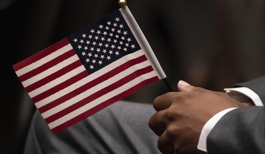 Leon Small, originally from Jamaica, holds a United States flag in a naturalization ceremony, Wednesday, April 28, 2021, in New York. While on the brink of furloughing 70% of its roughly 20,000 employees that summer, U.S. Citizenship and Immigration said almost overnight that it would end the year with the large surplus. (AP Photo/Mark Lennihan, File)