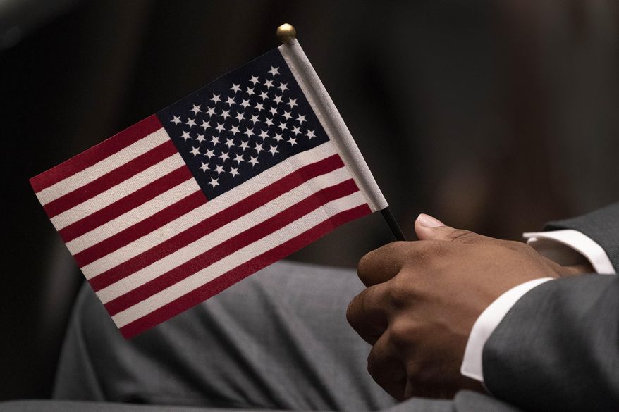 Leon Small, originally from Jamaica, holds a United States flag in a naturalization ceremony, Wednesday, April 28, 2021, in New York. While on the brink of furloughing 70% of its roughly 20,000 employees that summer, U.S. Citizenship and Immigration said almost overnight that it would end the year with the large surplus. (AP Photo/Mark Lennihan, File)