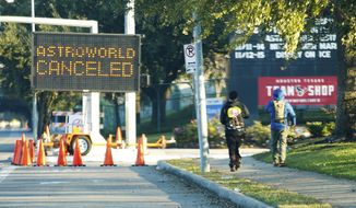 People walk past a sign announcing Astroworld is canceled outside NRG in Houston on Nov. 6, 2021. The 10 people who lost their lives in a massive crowd surge at the Astroworld music festival in Houston died from compression asphyxia, officials announced Thursday, Dec. 16, 2021. (Elizabeth Conley/Houston Chronicle via AP, File)