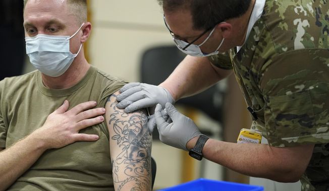 Staff Sgt. Travis Snyder, left, receives the first dose of the Pfizer COVID-19 vaccine given at Madigan Army Medical Center at Joint Base Lewis-McChord in Washington state, Dec. 16, 2020, south of Seattle. The Army says 98% of its active duty force had gotten at least one dose of the mandatory coronavirus vaccine as of this week’s deadline for the shots. (AP Photo/Ted S. Warren) ** FILE **