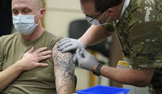 Staff Sgt. Travis Snyder, left, receives the first dose of the Pfizer COVID-19 vaccine given at Madigan Army Medical Center at Joint Base Lewis-McChord in Washington state, Dec. 16, 2020, south of Seattle. The Army says 98% of its active duty force had gotten at least one dose of the mandatory coronavirus vaccine as of this week’s deadline for the shots.  (AP Photo/Ted S. Warren) **FILE**