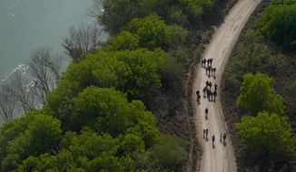 Migrants walk on a dirt road along the Rio Grande in Mission, Texas, on March 23, 2021, after crossing the U.S.-Mexico border. (AP Photo/Julio Cortez) ** FILE **