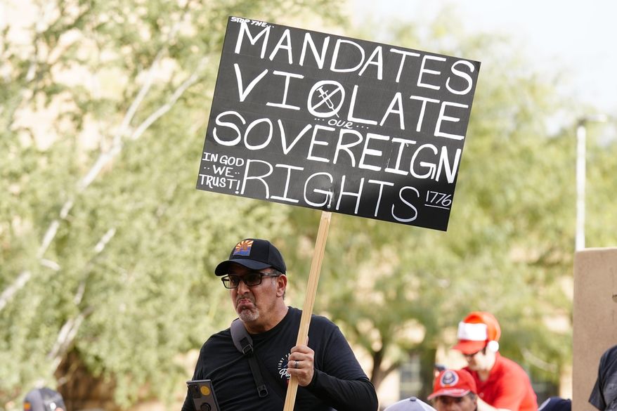 One of many anti-vaccine mandate activists holds a sign during a rally outside Phoenix City Council chambers as the city paused implementation of a federal COVID-19 vaccine mandate for the 14,000 city workers, Tuesday, Dec. 7, 2021, in Phoenix. On Friday, Dec. 17, 2021, a federal appeals court panel allowed President Joe Biden&#39;s COVID-19 vaccine mandate for larger private employers to move ahead. (AP Photo/Ross D. Franklin) **FILE**