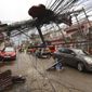 Cars pass by a toppled electrical post due to Typhoon Rai in Surigao city, Surigao del Norte, southern Philippines as power supply remain down on Sunday Dec. 19, 2021. The death toll in the strongest typhoon to batter the Philippines this year continues to rise and the governor of an island province especially hard-hit by Typhoon Rai said there may be even greater devastation that has yet to be reported. (AP Photo/Jilson Tiu)