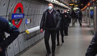 Commuters, some wearing face masks to curb the spread of COVID-19, walk at Westminster underground station in central London, Monday Dec. 20, 2021. Britain’s health secretary has refused to rule out imposing tougher COVID-19 restrictions before Christmas amid the rapid rise of infections and continuing uncertainty about the omicron variant. (Victoria Jones/PA via AP)