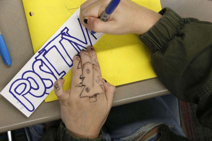 An 8th grader works on a class project at Paw Paw Middle School on Thursday, Dec. 2, 2021, in Paw Paw, Michigan. The students were asked to write a word that was important to them and their work in the classroom. They then added the words to a poster to serve as a class "contract." The district has upped its social-emotional curriculum during the pandemic, as more students struggle. That is common nationwide. A recent AP-NORC/MTV poll found that nearly half of U.S. teens said the pandemic has made it harder to be happy and maintain their mental health. (AP Photo/Martha Irvine) ** FILE **
