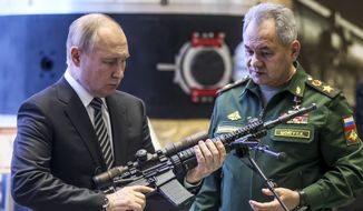 Russian President Vladimir Putin, left, and Russian Defense Minister Sergei Shoigu visit an military exhibition after attending an extended meeting of the Russian Defense Ministry Board at the National Defense Control Center in Moscow, Russia, Tuesday, Dec. 21, 2021. The Russian president on Tuesday reiterated the demand for guarantees from the U.S. and its allies that NATO will not expand eastward, blaming the West for current tensions in Europe. (Mikhail Metzel, Sputnik, Kremlin Pool Photo via AP)