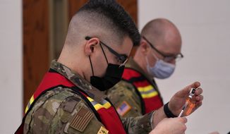 National Guardsmen prepare Pfizer-BioNTech vaccinations at a COVID-19 clinic at the Augusta Armory, Tuesday, Dec. 21, 2021, in Augusta, Maine. (AP Photo/Robert F. Bukaty)