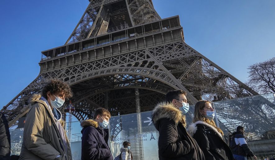 People wearing face masks to protect against COVID-19 walk past the Eiffel Tower in Paris, Tuesday, Dec. 21, 2021. Nations across Europe have moved to reimpose tougher measures to stem a new wave of COVID-19 infections spurred by the highly transmissible omicron variant. (AP Photo/Michel Euler) ** FILE **
