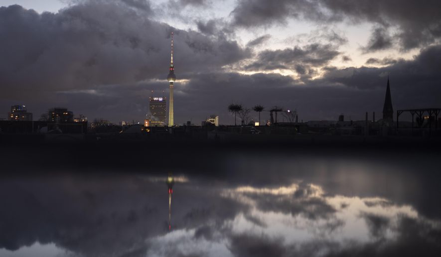 Dark clouds covering the sky and reflected in a puddle, in the German capital Berlin, Monday, Dec. 20, 2021. Many governments in Europe and the U.S. are confronting similar dilemmas over how hard to come down in the face of omicron, which appears more transmissible than the previous delta variant that itself led to surges in many parts of the world. (AP Photo/Markus Schreiber)