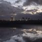 Dark clouds covering the sky and reflected in a puddle, in the German capital Berlin, Monday, Dec. 20, 2021. Many governments in Europe and the U.S. are confronting similar dilemmas over how hard to come down in the face of omicron, which appears more transmissible than the previous delta variant that itself led to surges in many parts of the world. (AP Photo/Markus Schreiber)